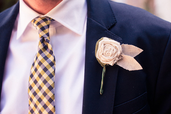 Groom wearing yellow and dark blue plaid tie with a tan linen boutonniere shaped as a rose - photo by Orange County based wedding photographers Mark Brooke
